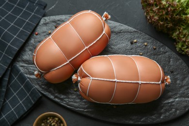 Photo of Tasty boiled sausages on dark textured table, flat lay