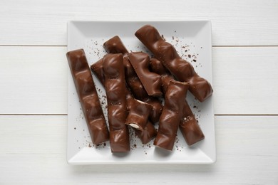 Photo of Tasty chocolate bars on white wooden table, top view
