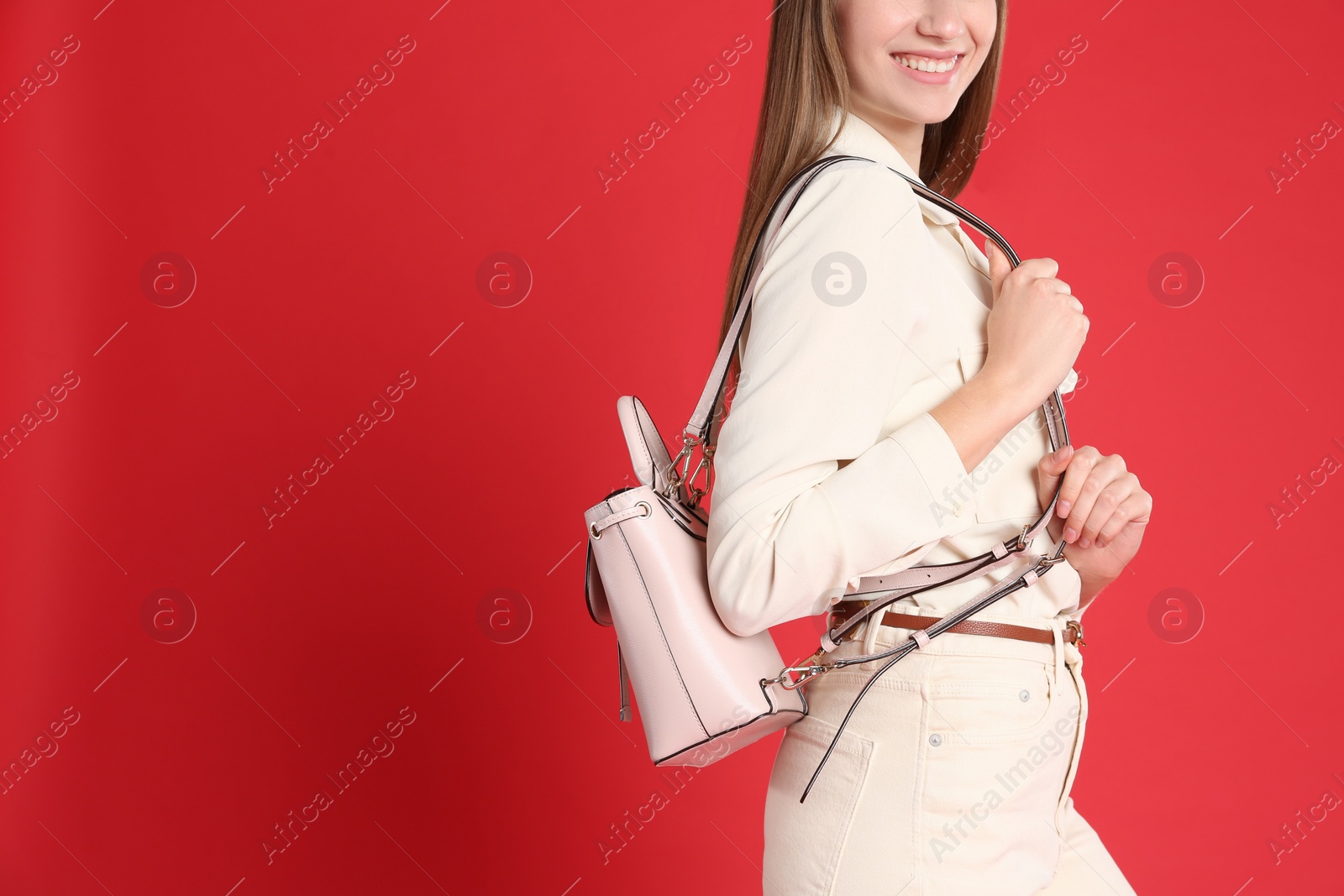 Photo of Young woman in casual outfit with stylish bag on red background, closeup. Space for text