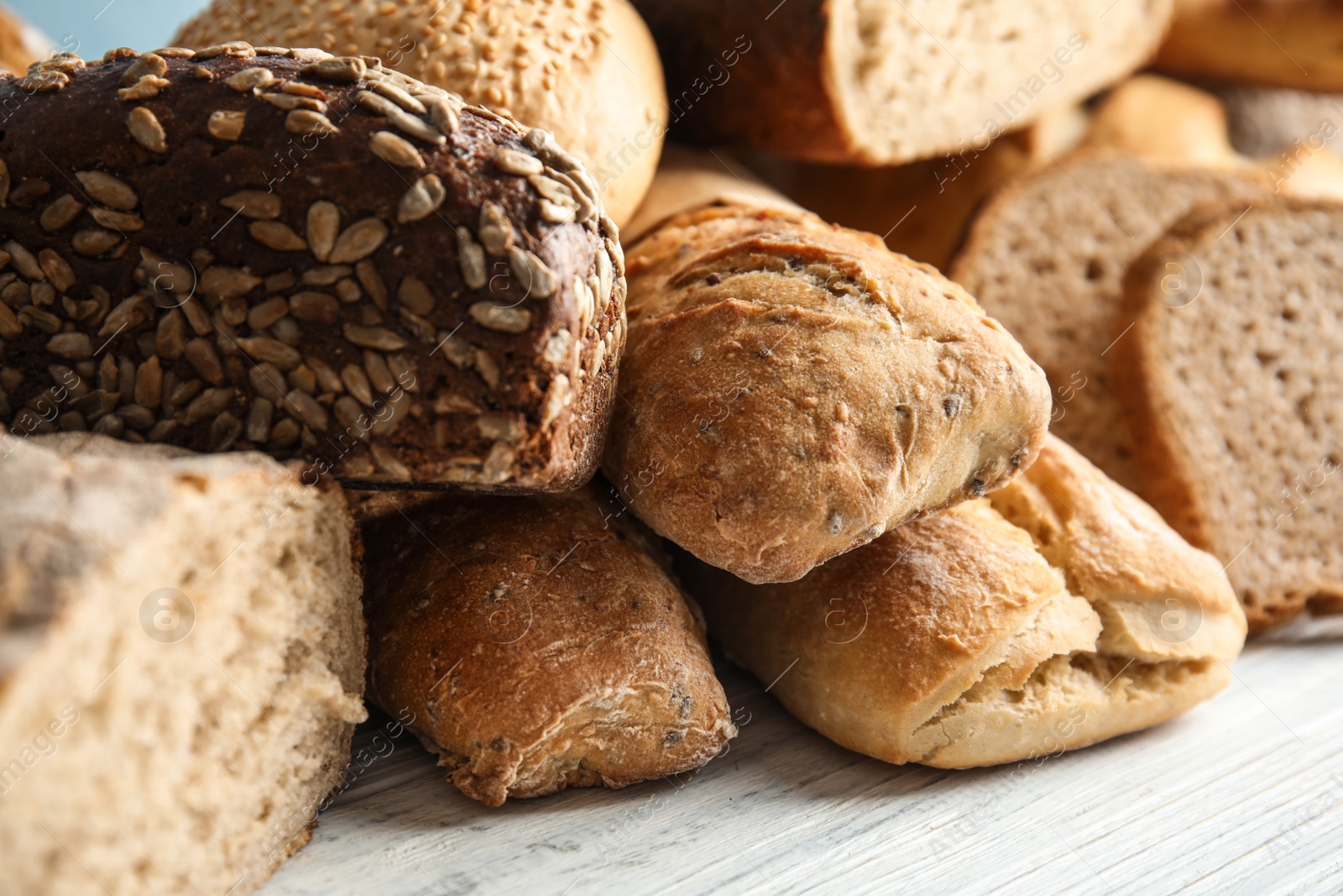 Photo of Different kinds of fresh bread on wooden table, closeup