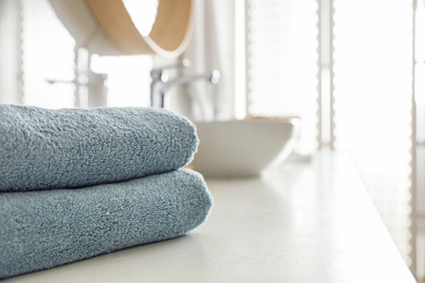 Photo of Stack of clean towels on countertop in bathroom. Space for text