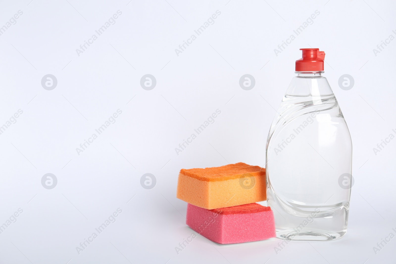 Photo of Bottle of detergent and sponges on white background