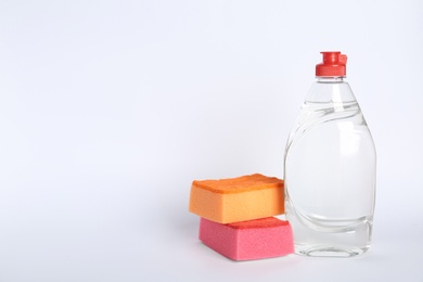 Bottle of detergent and sponges on white background