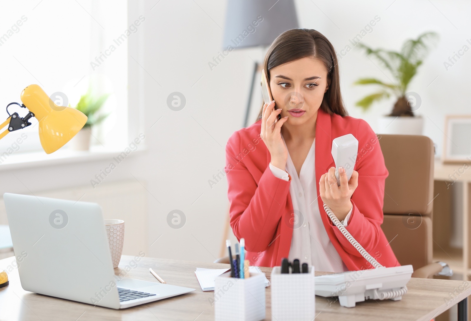 Photo of Young woman talking on phone at workplace