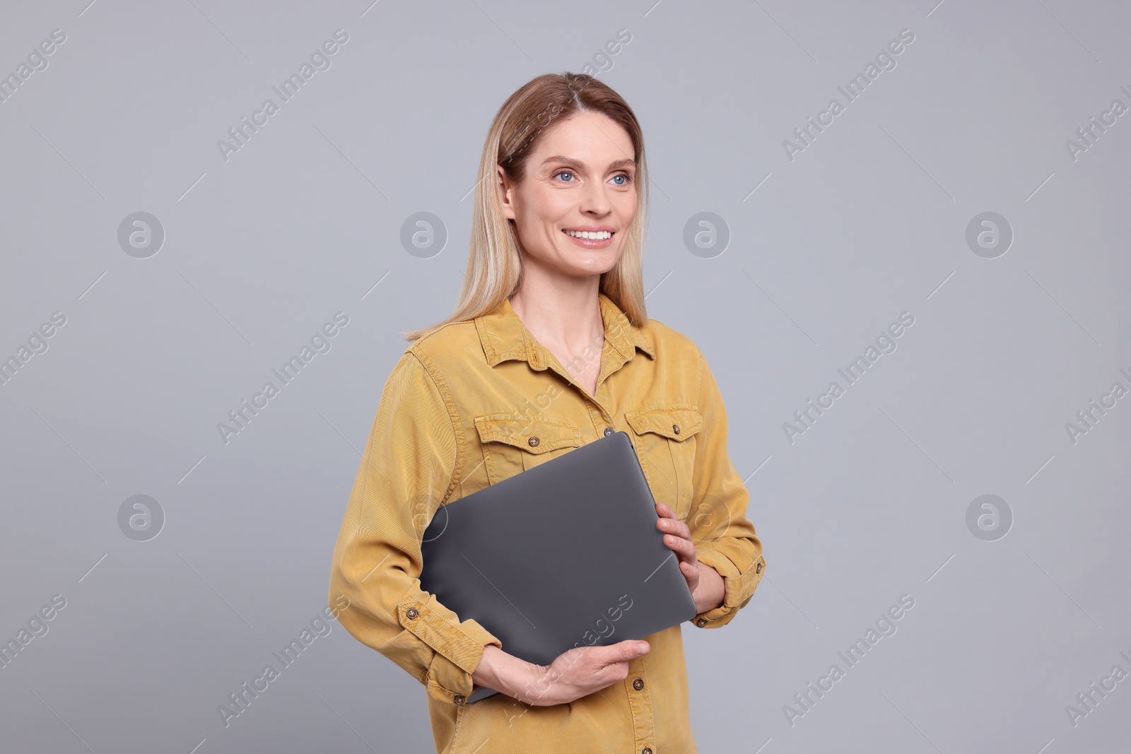 Photo of Happy woman with laptop on light grey background