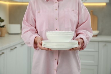 Woman holding plates in kitchen, closeup view
