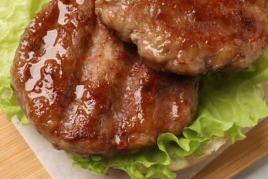 Photo of Delicious fried patties, lettuce and bun on board, closeup. Making hamburger