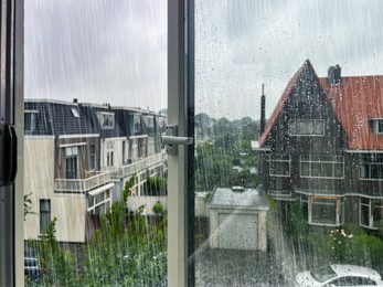 Beautiful cityscape with buildings on rainy day, view through open window