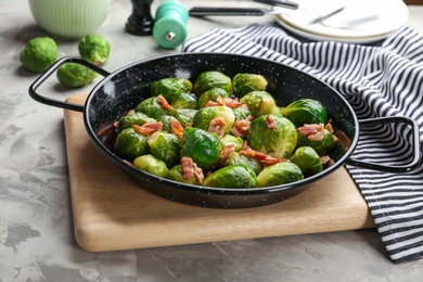 Photo of Tasty roasted Brussels sprouts with bacon on light grey table