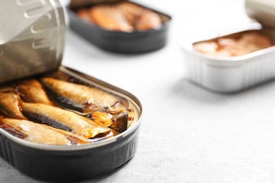 Tin can with sprats on light table, closeup. Space for text