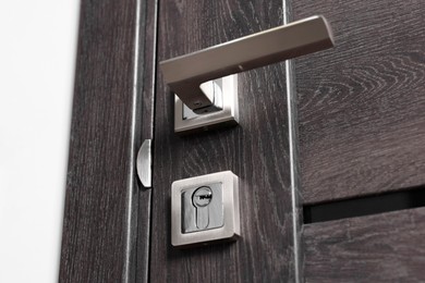 Photo of Open wooden door with metal handle indoors, closeup