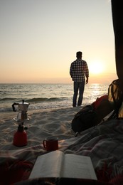 Photo of Man enjoying sunset on seashore. Beach camping