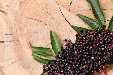 Photo of Pile of tasty elderberries (Sambucus) and leaves on wooden stump, top view. Space for text