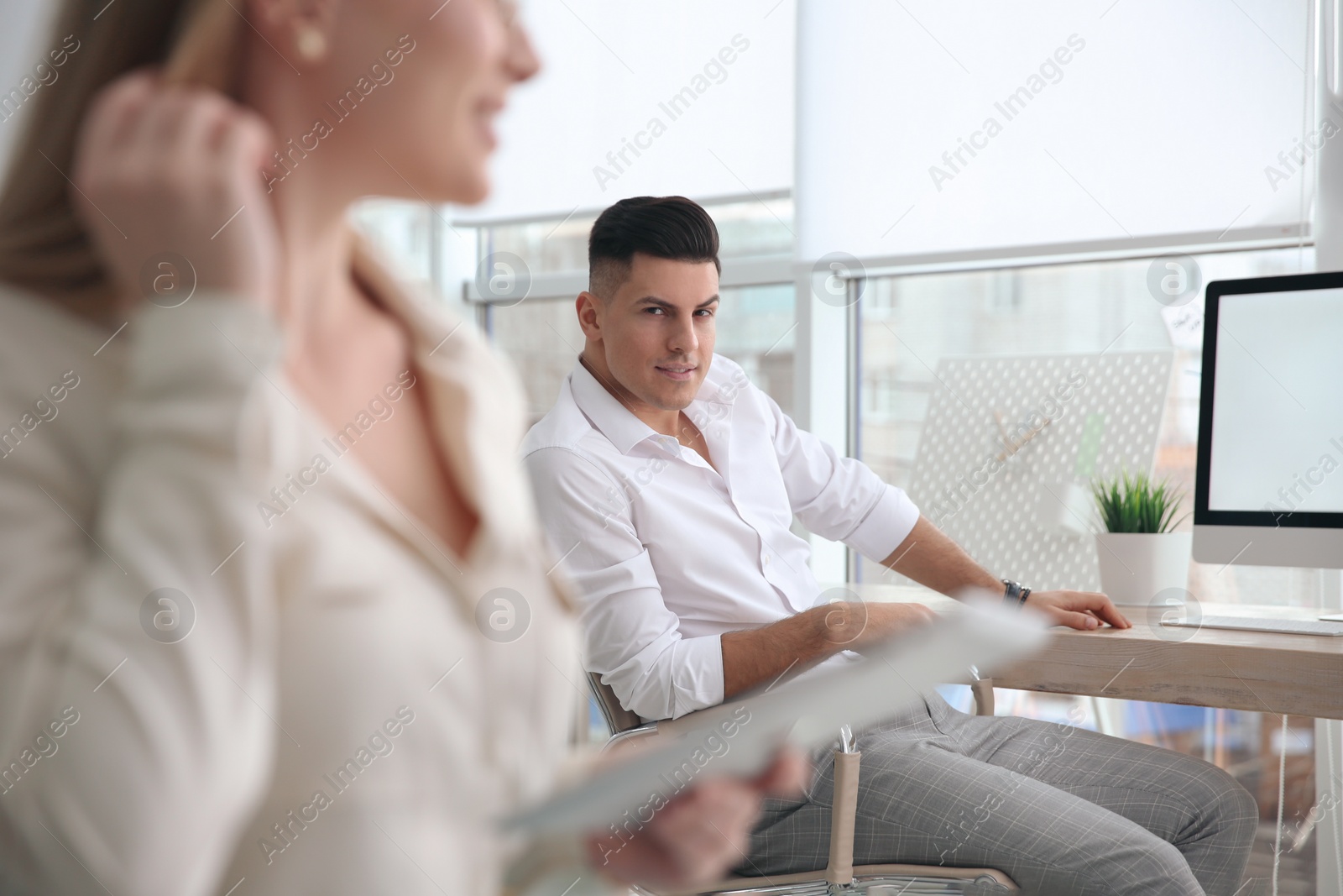 Photo of Man looking at his colleague in office. Flirting on job