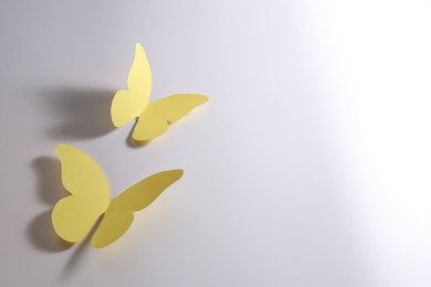 Photo of Yellow paper butterflies on light background. Space for text