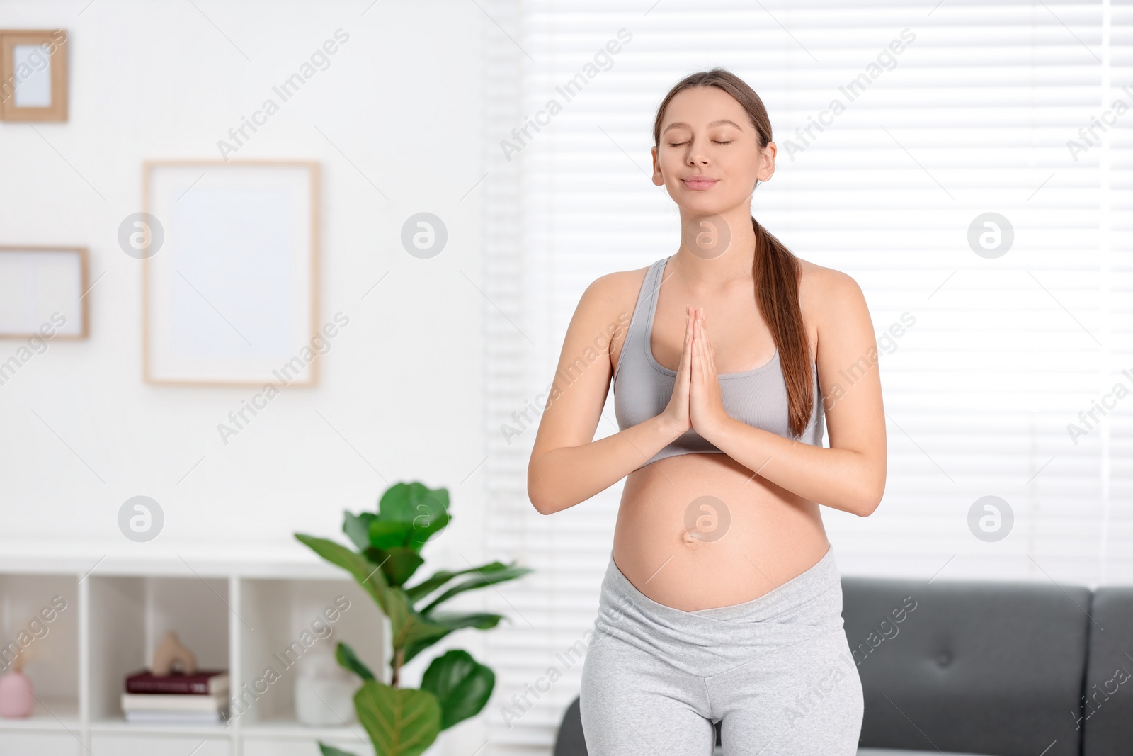 Photo of Pregnant woman meditating at home, space for text. Doing yoga
