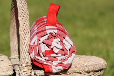 Photo of Checkered tablecloth on picnic basket outdoors, closeup
