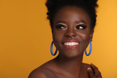 Photo of Fashionable portrait of beautiful happy woman with makeup on orange background, space for text
