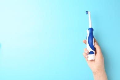 Photo of Woman holding electric toothbrush against color background