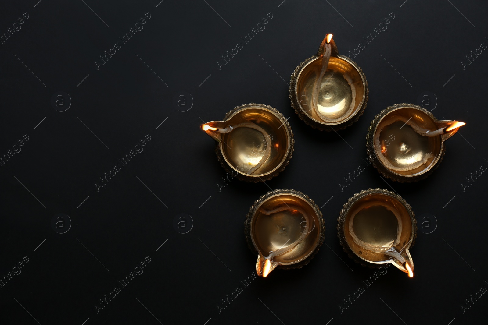 Photo of Lit diyas on dark background, flat lay with space for text. Diwali lamps