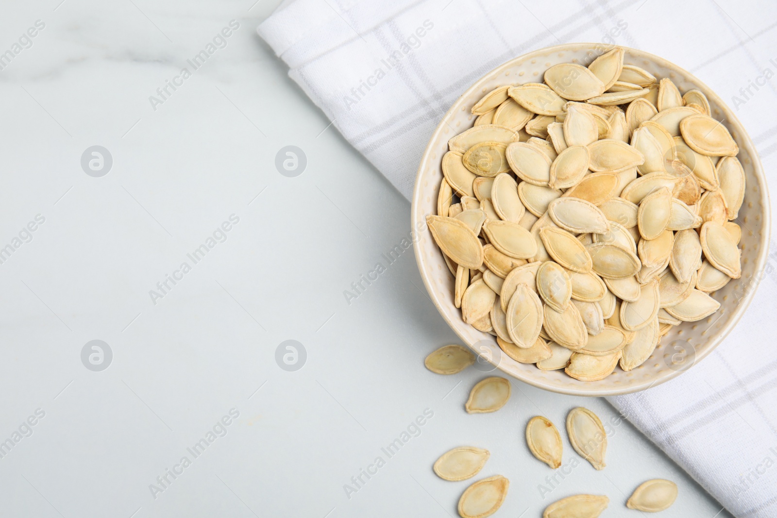 Photo of Bowl with pumpkin seeds on white table, flat lay. Space for text