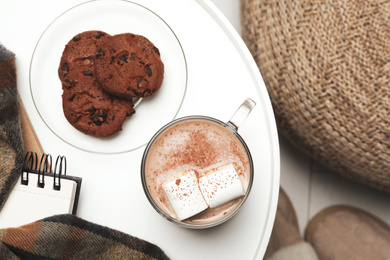Cup of delicious hot cocoa with marshmallows and cookies on white table, top view. Winter drink
