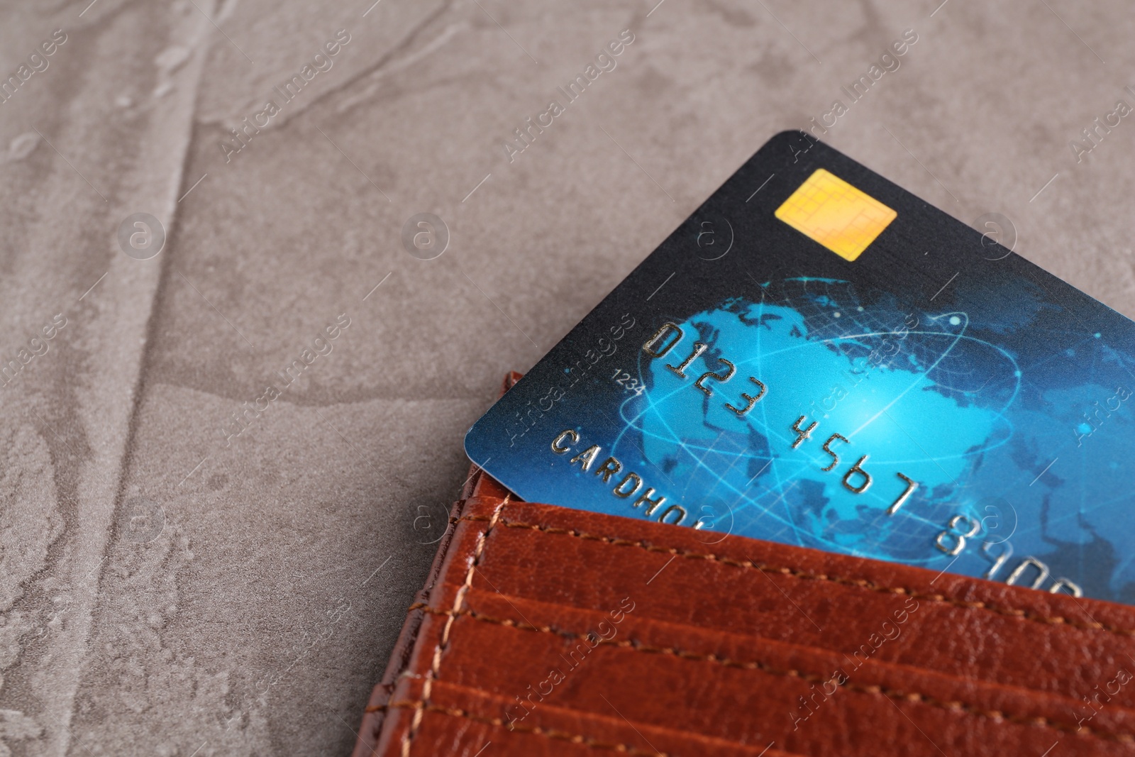 Photo of Credit card in leather wallet on grey textured table, closeup