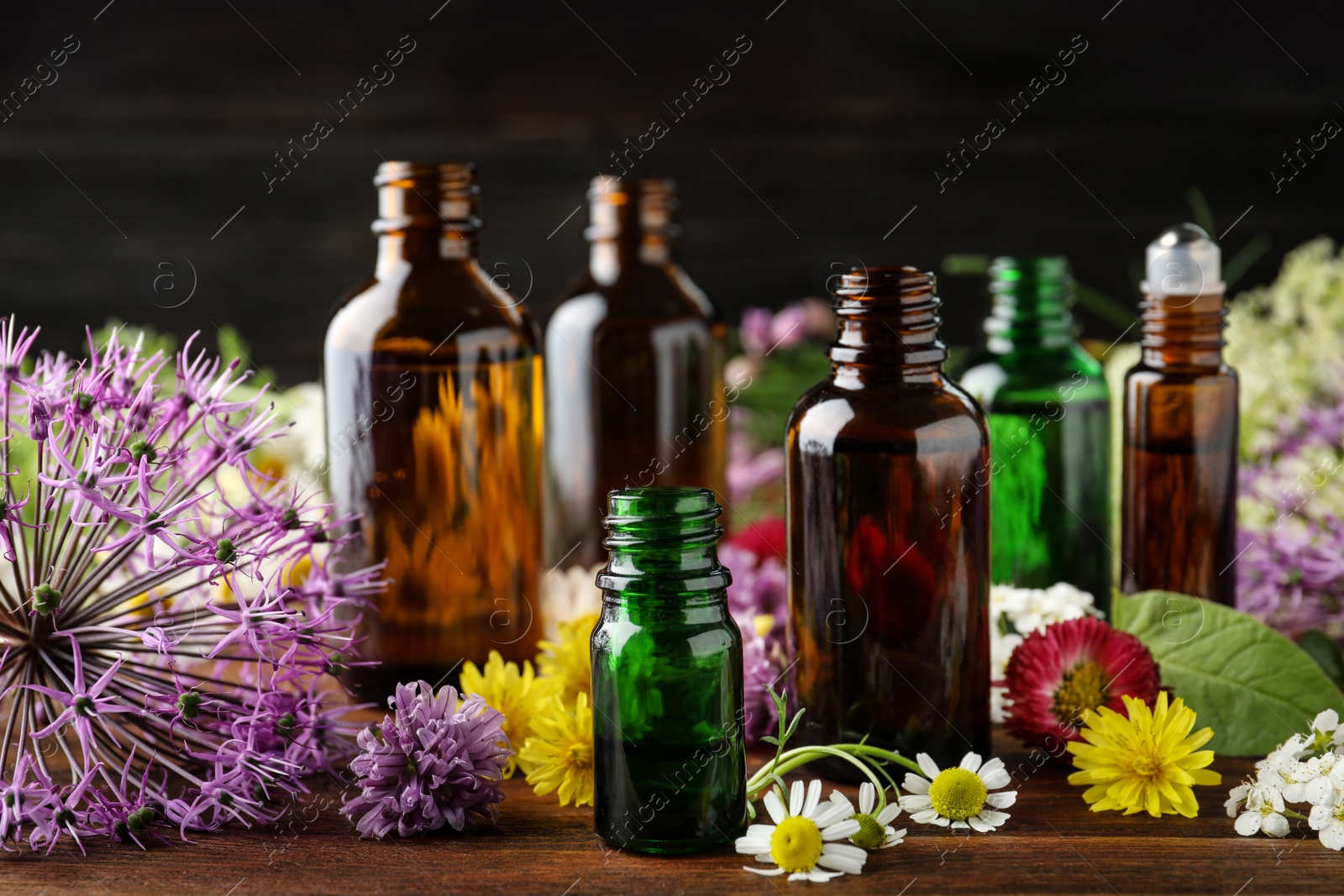 Photo of Different bottles of essential oils and flowers on table