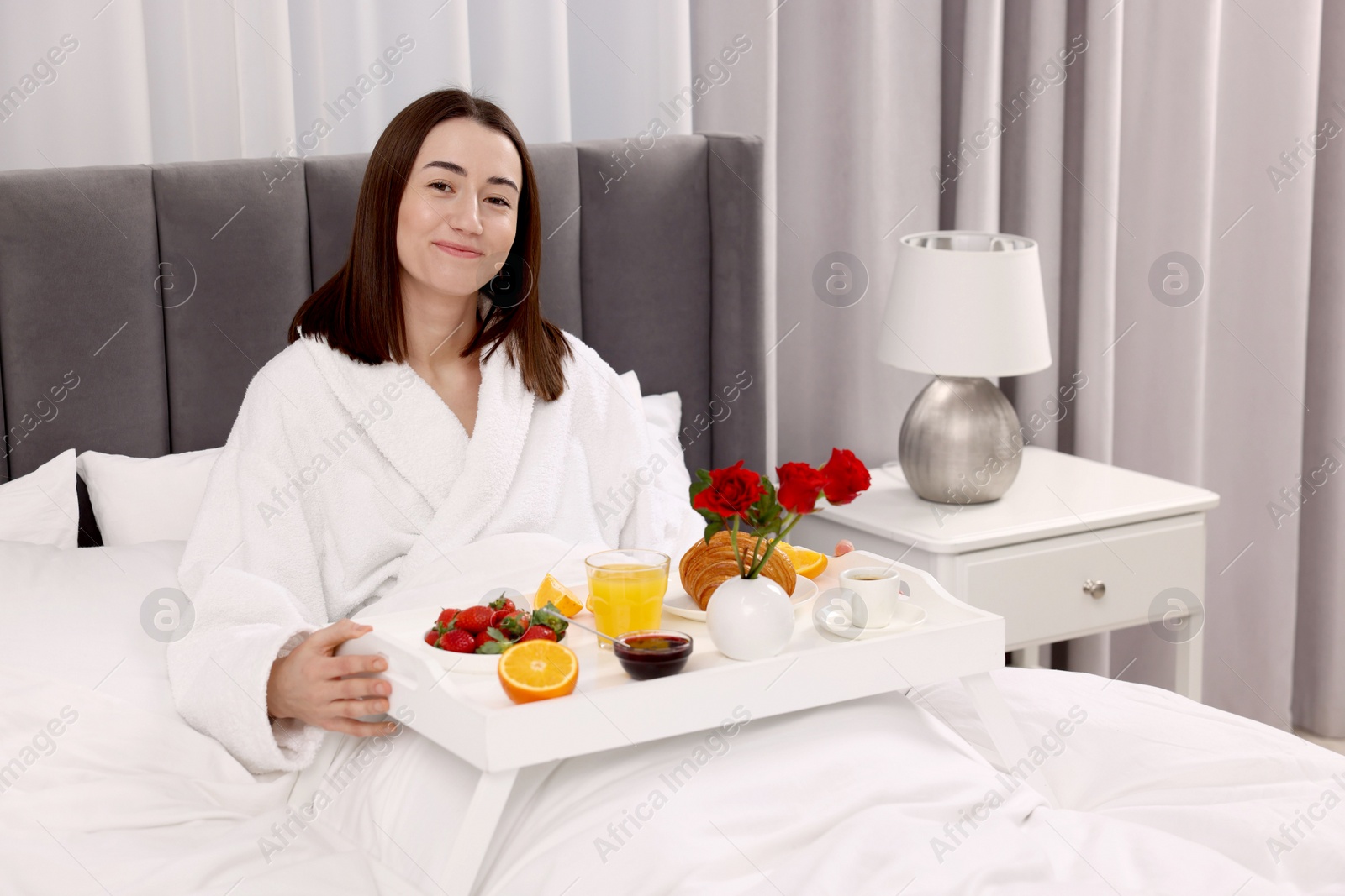 Photo of Young woman having breakfast in bed at home