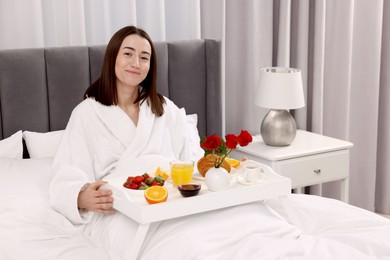 Young woman having breakfast in bed at home