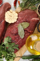 Photo of Pieces of raw beef meat, herbs and spices on table, flat lay