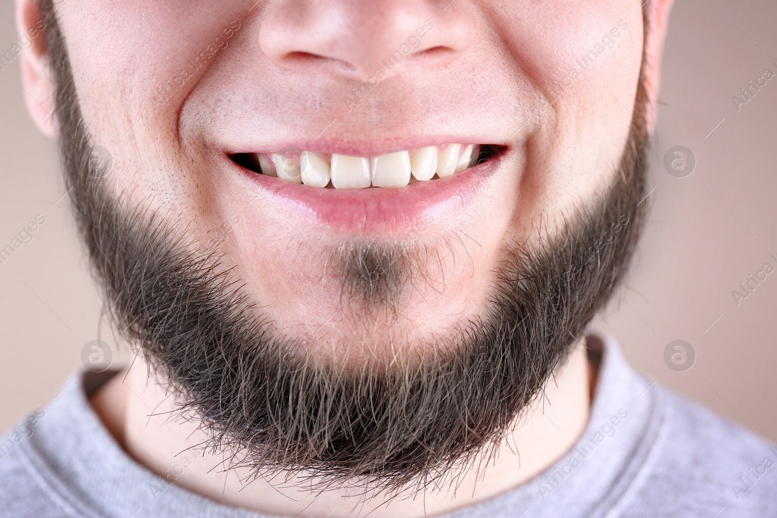 Photo of Young man with healthy teeth smiling on color background, closeup