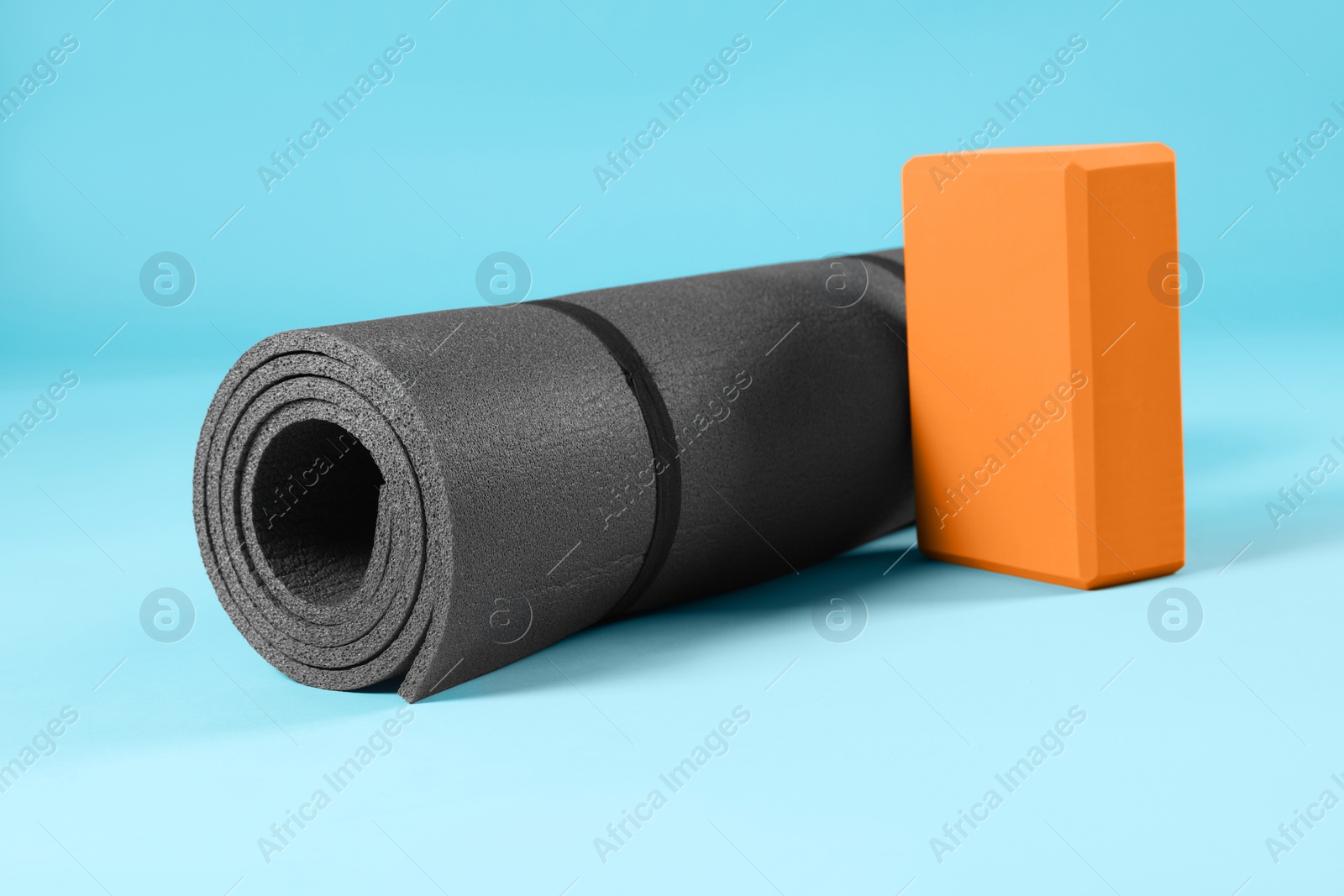 Photo of Exercise mat and yoga block on light blue background