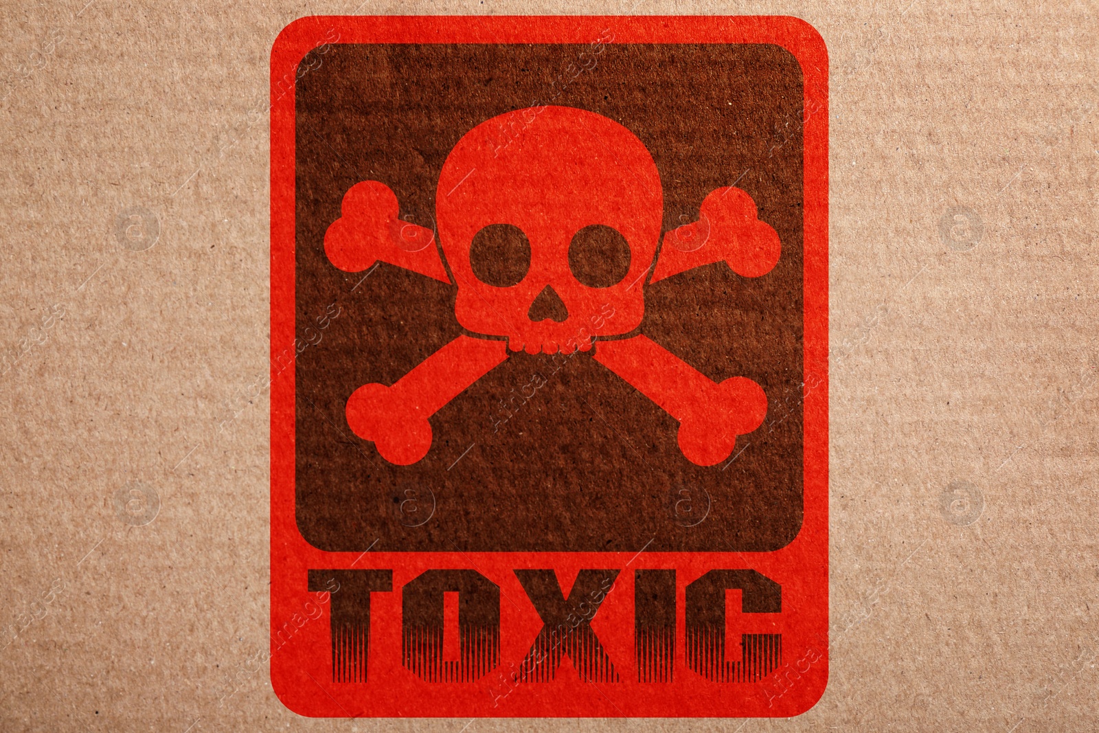 Image of Hazard warning sign (skull-and-crossbones symbol and word TOXIC) on cardboard, top view