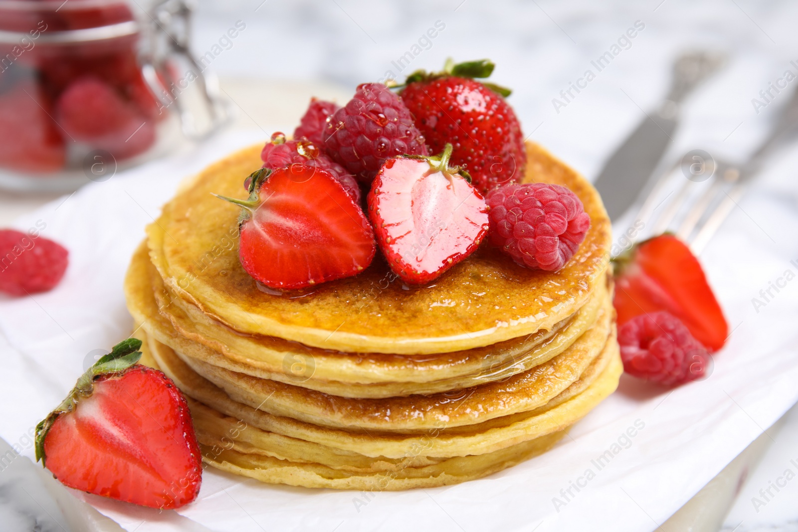 Photo of Tasty pancakes with fresh berries and honey on table, closeup