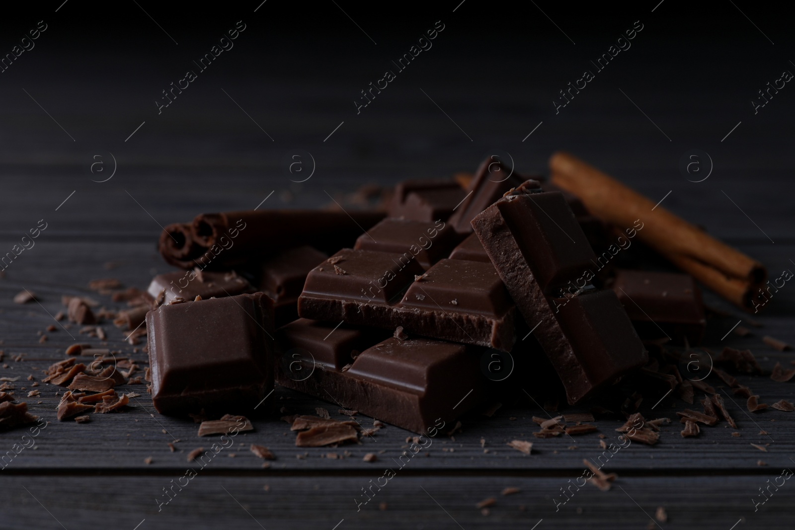 Photo of Delicious milk chocolate and cinnamon on wooden table