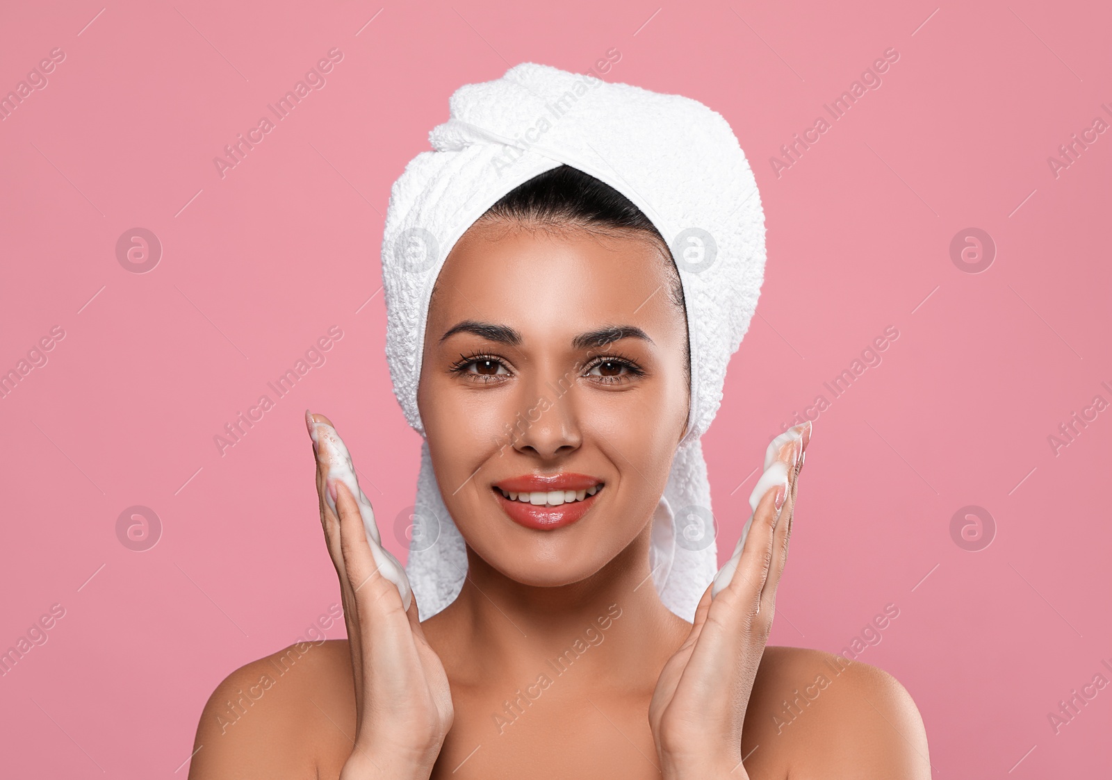 Photo of Beautiful woman applying facial cleansing foam on pink background