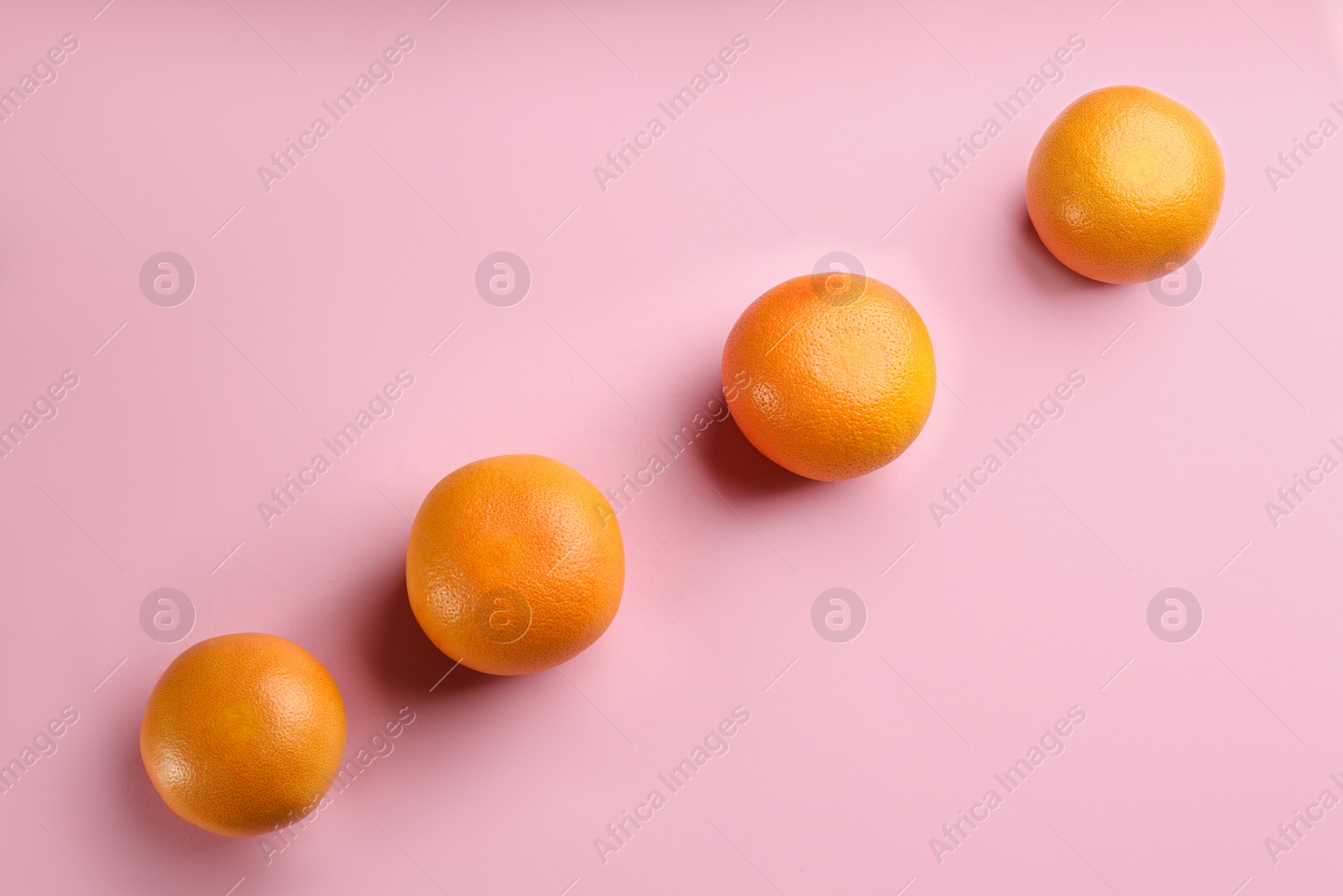 Photo of Tasty ripe grapefruits on pink background, flat lay