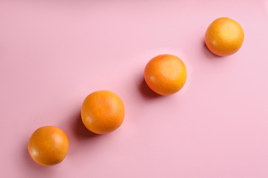 Photo of Tasty ripe grapefruits on pink background, flat lay