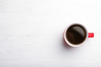 Ceramic cup with hot aromatic coffee on wooden background, top view