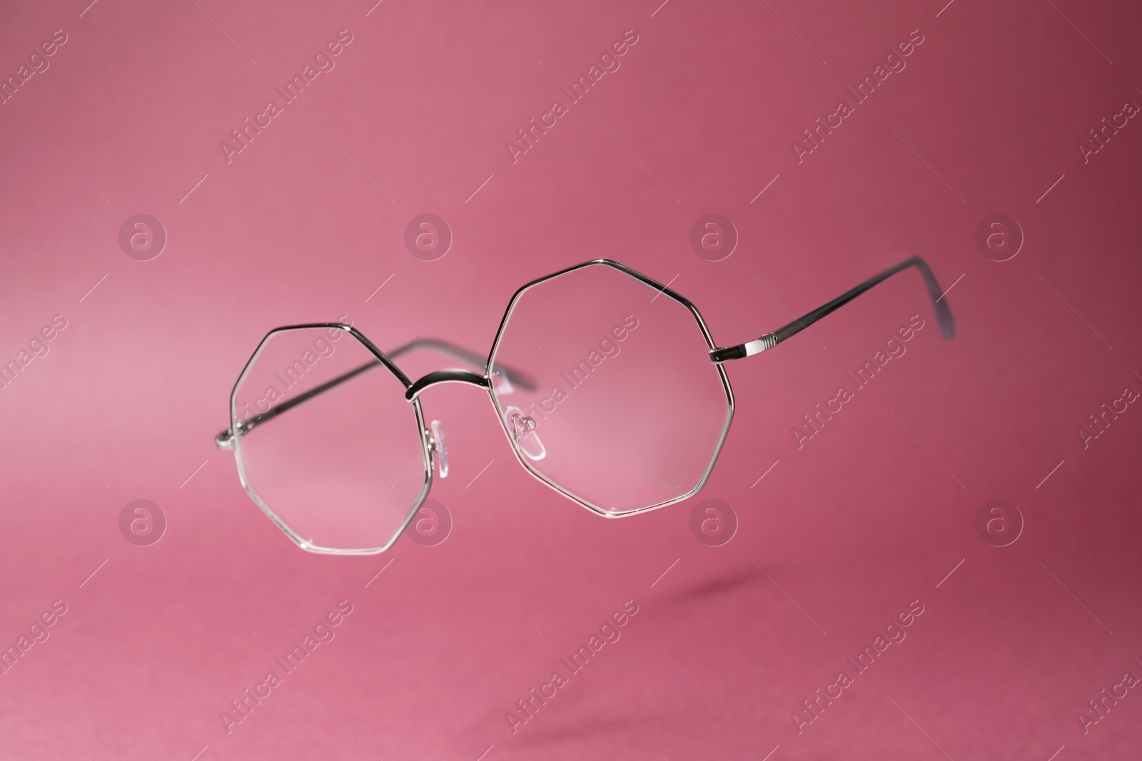 Photo of Stylish pair of glasses with metal frame on pink background