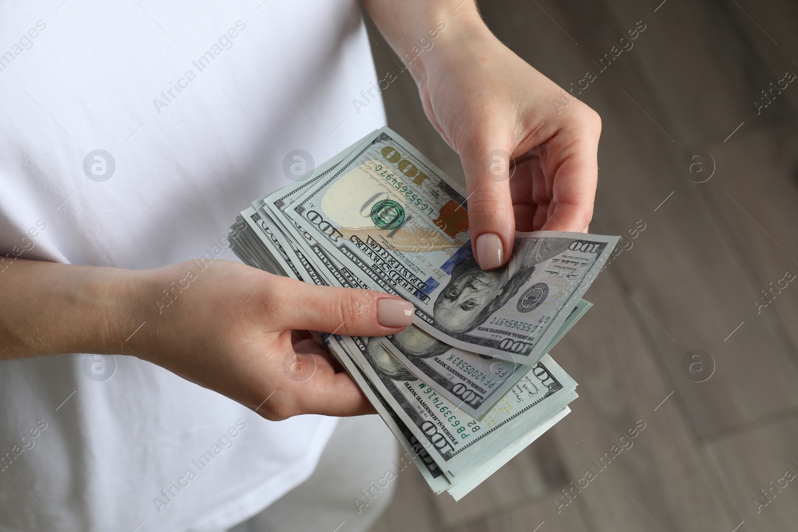 Photo of Money exchange. Woman counting dollar banknotes indoors, closeup