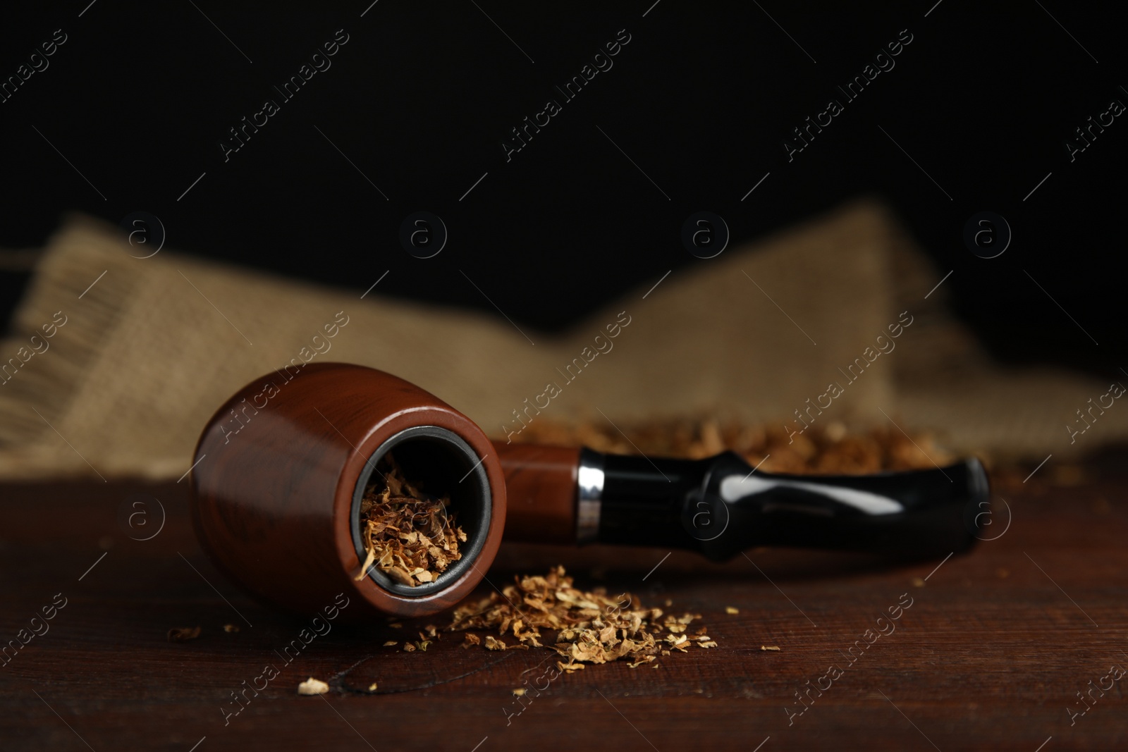 Photo of Classic smoking pipe with tobacco on wooden table