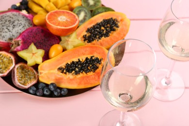 Photo of Delicious exotic fruits and wine on pink wooden table