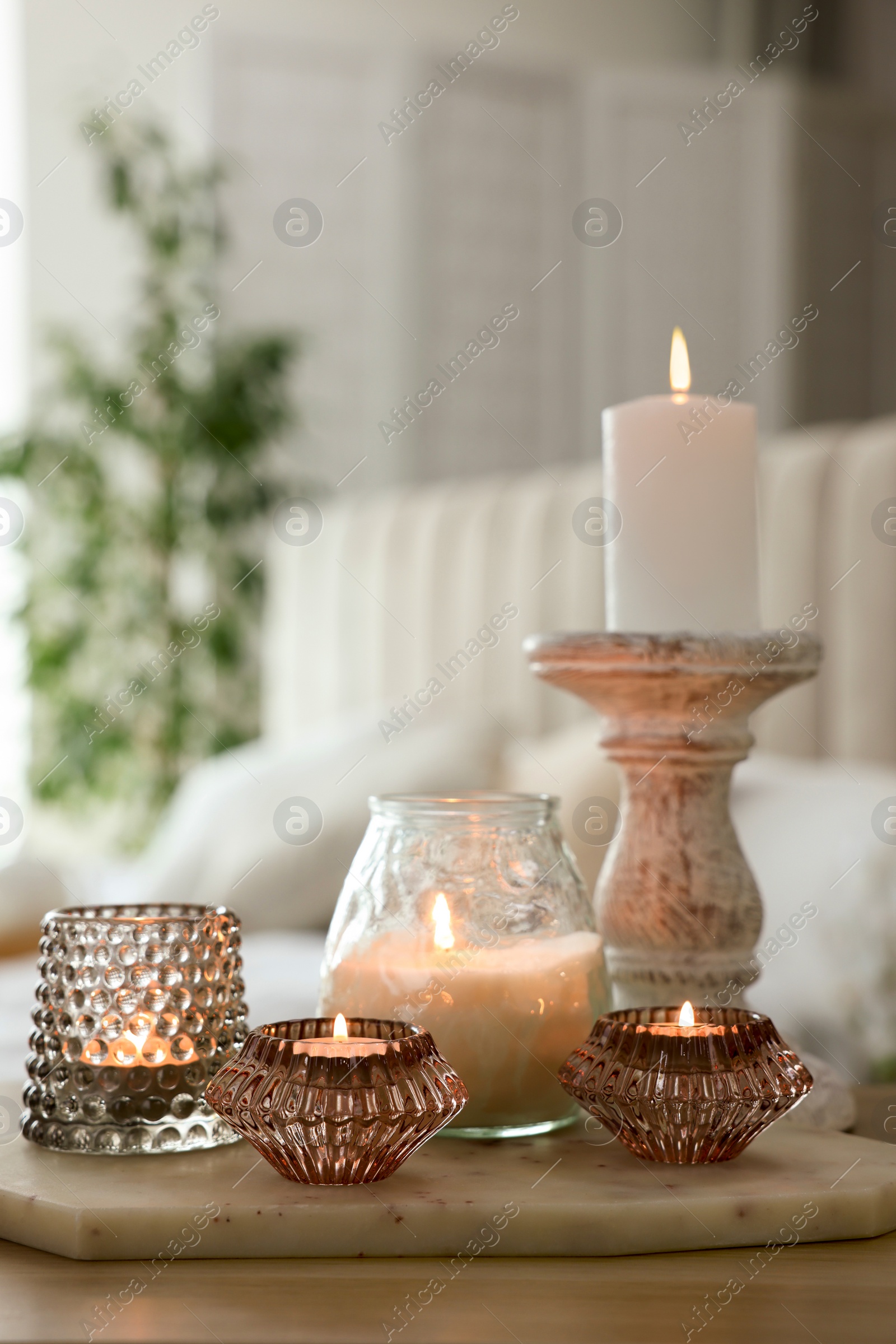 Photo of Set of scented candles and candlestick on wooden table in room