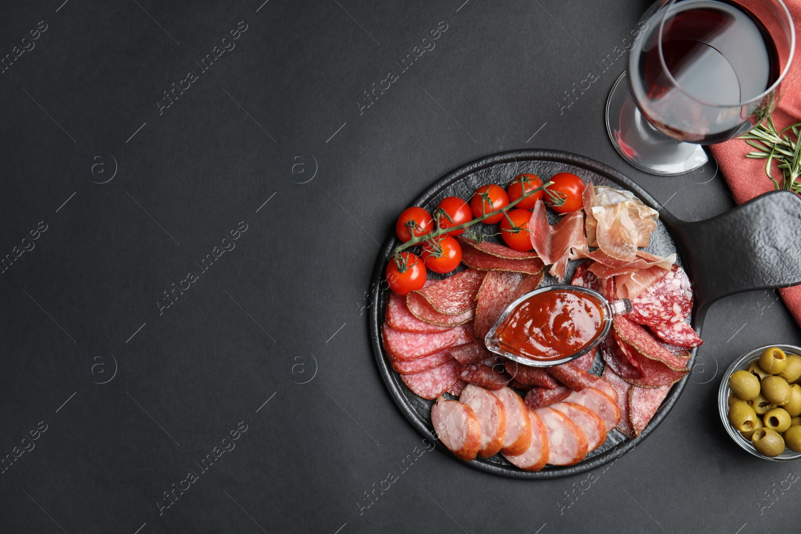 Photo of Different types of sausages with sauce served on black background, flat lay. Space for text