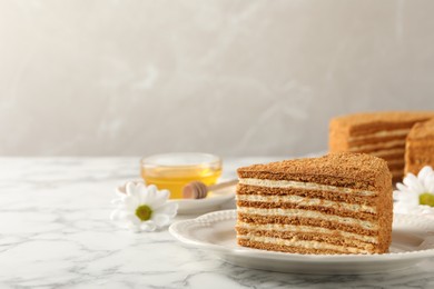 Photo of Slice of delicious layered honey cake served on white marble table. Space for text