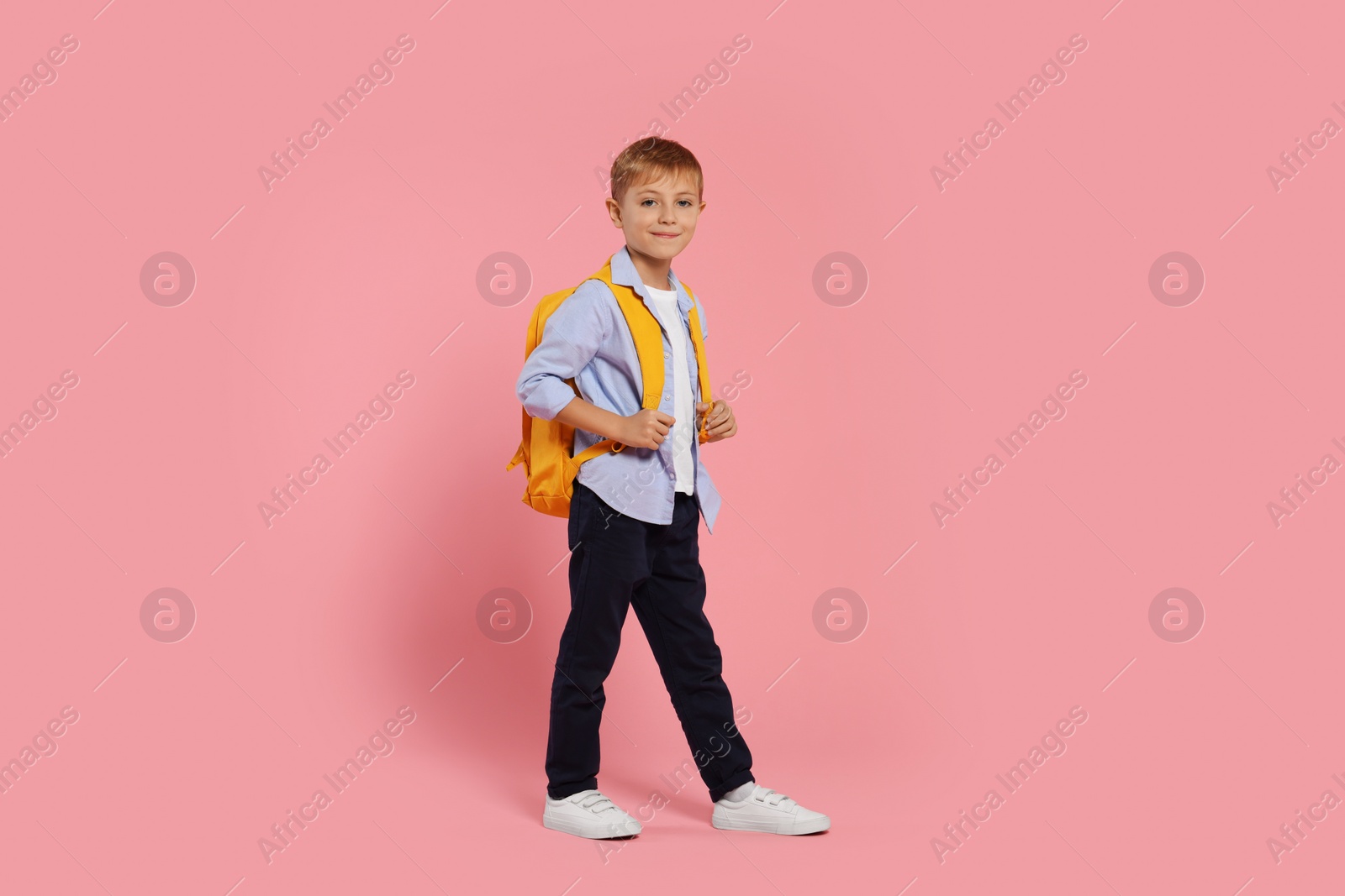 Photo of Happy schoolboy with backpack on pink background