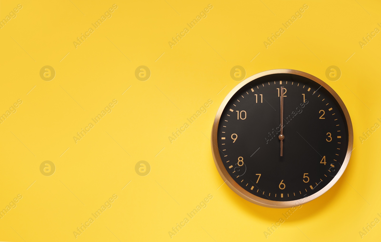 Photo of Stylish round clock on yellow background, top view with space for text. Interior element