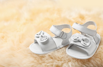 Photo of Pair of cute baby sandals on fuzzy fabric